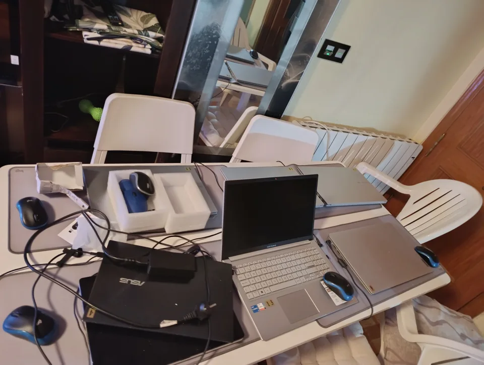 Un portátil abierto sobre la mesa, con ratón y cajas, la noche de la entrega
