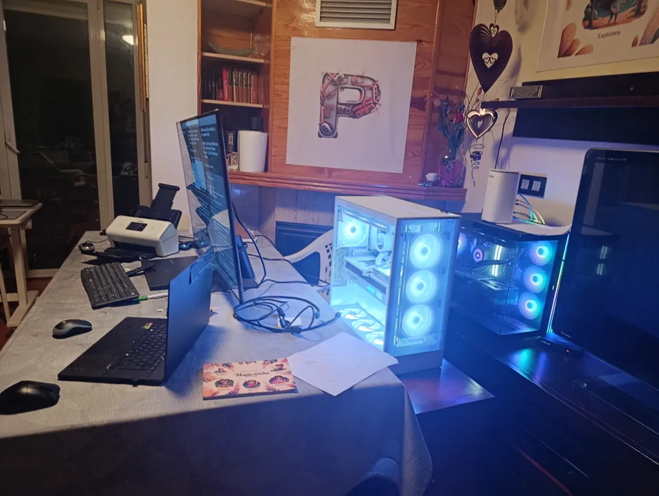 El salón-oficina de la casa: mesa con portátil y monitor, las dos torres encendidas, la P de ProSoftom en la pared y un cuento de Magicandia sobre la mesa