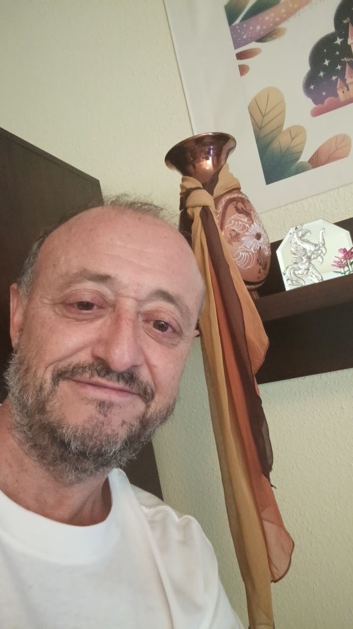 Lucas Valera Corbalán sonriendo con los labios cerrados, junto a un jarrón de cerámica con un pañuelo anudado.